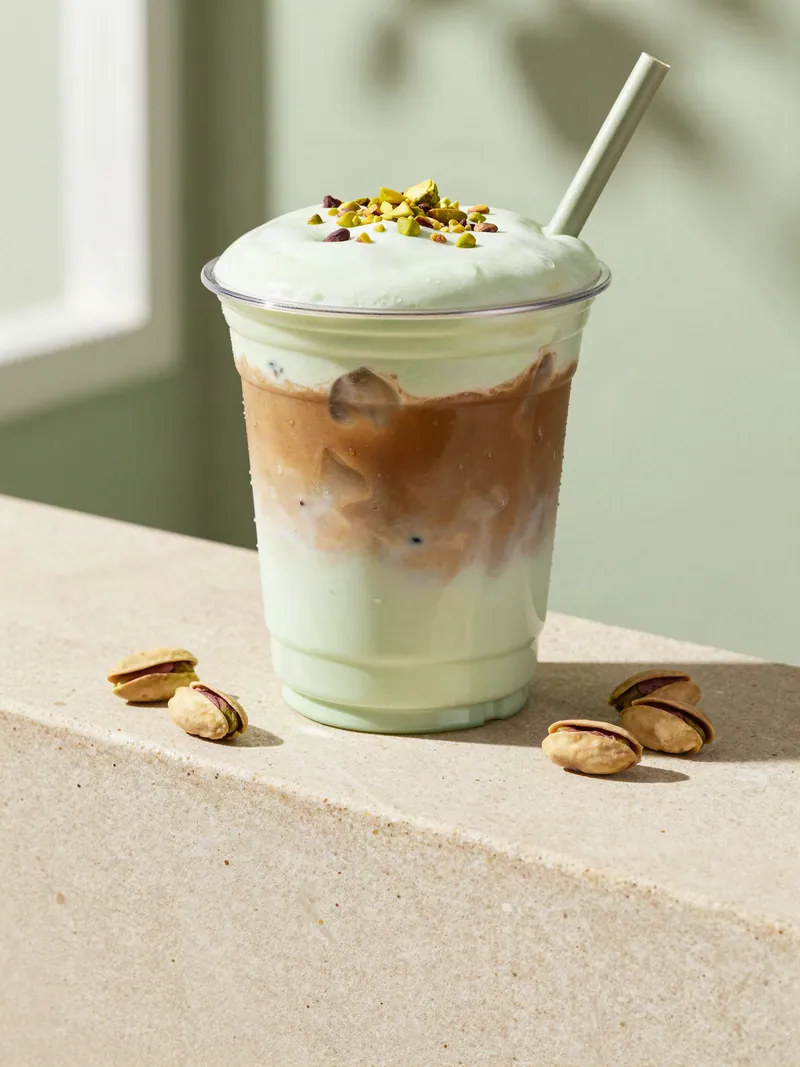 An iced pistachio shaken espresso topped with pistachio foam and crushed pistachios
