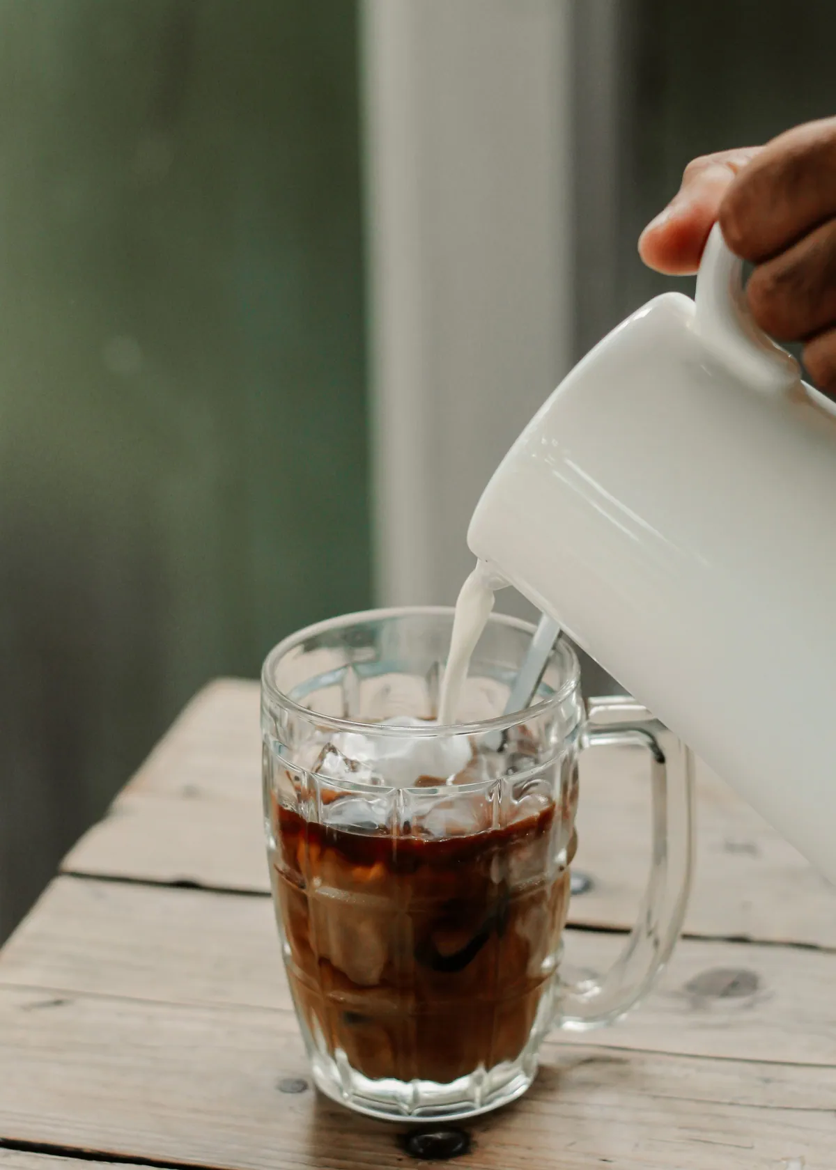 Milk being poured over iced coffee