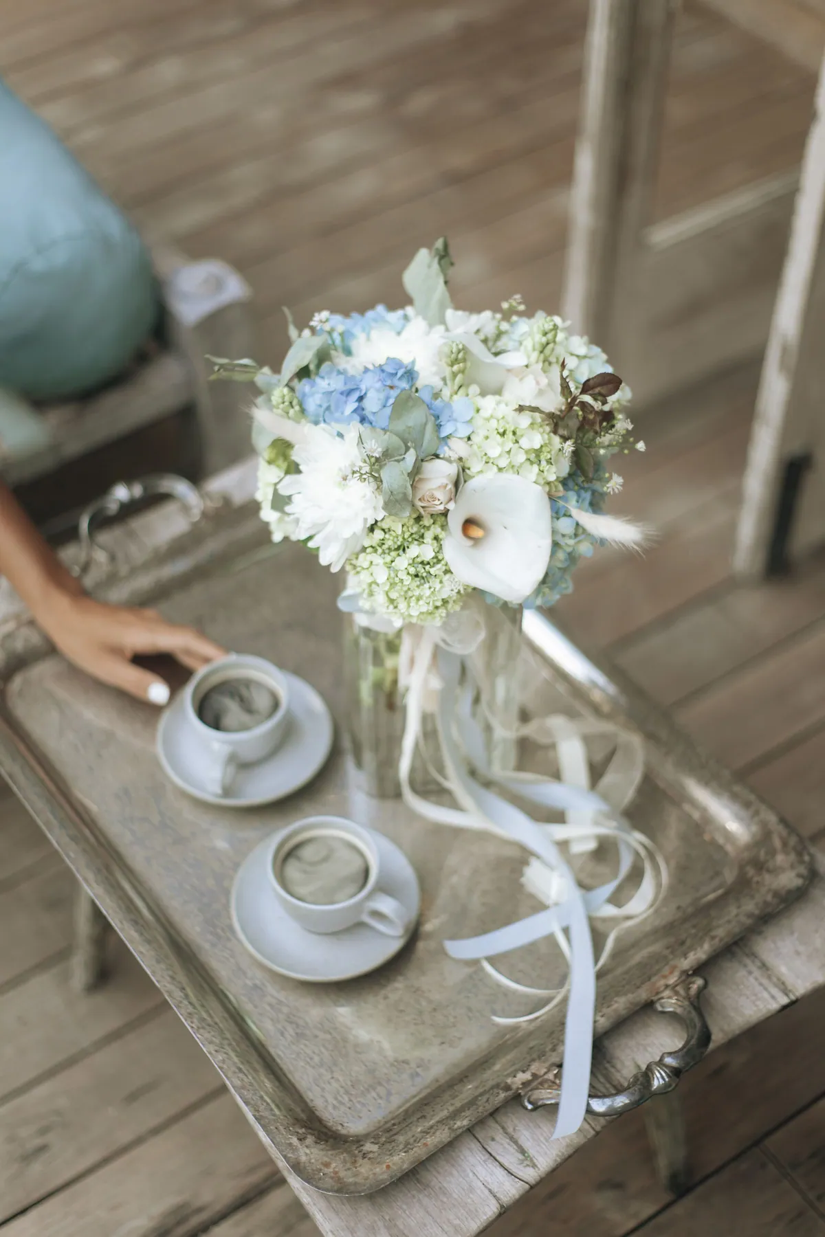 Coffee cups beside a wedding bouquet on a silver tray